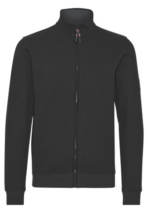 Melnā zip-žakete ar augstu apkakli, garām piedurknēm, ribotām aprocēm un apakšmalu. Izgatavota no gludas auduma bez redzamām rakstiem vai akcentiem.