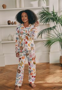 Ensemble de pyjama coloré avec divers motifs de nourriture et de papillons. Confectionné en tissu doux avec manches longues et pantalon, agrémenté de détails de bordure contrastante.