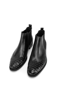 Botines de cuero negro con puntera y lados de charol con grabado de cocodrilo, parte superior lisa, paneles elásticos y tiradores.