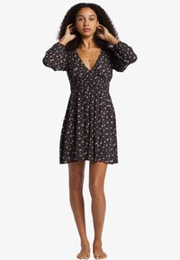 Black floral dress with a deep V-neckline, elasticated waist, and puff sleeves. Features colorful floral prints on a dark background.
