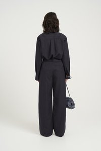 Tengerész csíkos, két részes öltözet, amely egy laza szabású pólóból és bővebb nadrágból áll, kiegészítve egy kis crossbody táskával.