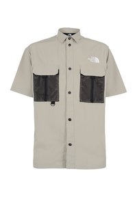 Camicia beige a maniche corte con colletto, tasche in rete nere e chiusura frontale a bottoni. Logo stampato sul petto.