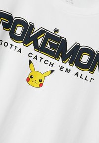 Valge puuvillane T-särk, millel on keskel suur must ja kollane "POKÉMON" tekst ning graafika Pikachust.