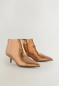Bottines en bronze avec une texture en imitation serpent, dotées d'un bout pointu et d'un talon bas et effilé, fermées par une fermeture éclair latérale.