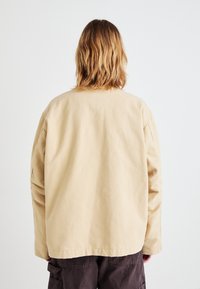 Beżowa, lekka kurtka z mieszanki bawełny o luźnym kroju, opadających ramionach i minimalistycznym designie, z dołem sięgającym poniżej talii.