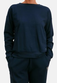 Granatowa bluza z miękkiego materiału, o luźnym kroju, z okrągłym dekoltem i subtelnym logo na dole.