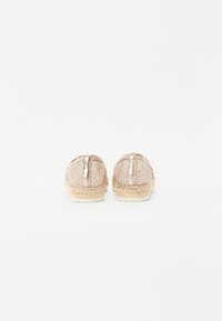 Espadriller med en lys beige vevd overdel, metalliske detaljer og en flettet jutesåle. Har en glatt bakre hælflik.