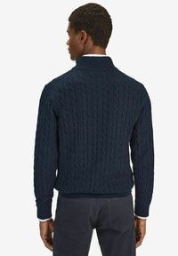 Mörkblå stickad tröja med flätmönster, ribbad krage och mudd, samt en avslappnad passform. Bekväm bakvy som framhäver textur och design.