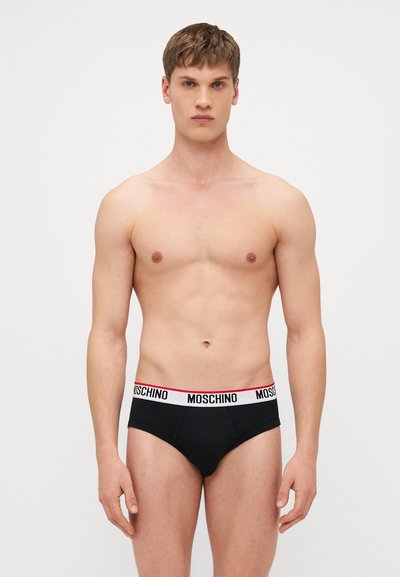 Slips pour hommes noirs avec une ceinture élastique blanche et rouge portant la marque "MOSCHINO". Tissu lisse, design classique et forme ajustée.