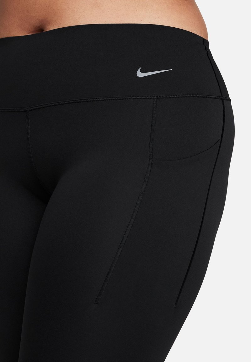 Leggings negras elásticas con una cinturilla elástica y un pequeño logo plateado en el lateral. Cuentan con un bolsillo trasero y una textura suave.