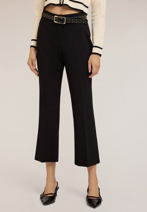 Pantalones negros con una textura suave, presentan un diseño de pierna ancha y un cinturón negro con tachuelas y hebilla dorada para un detalle adicional.