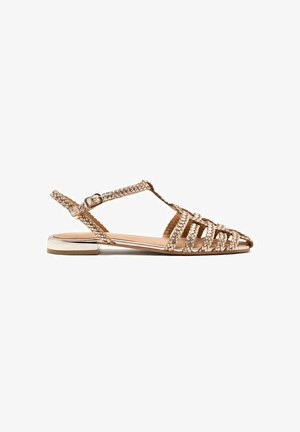 Sandali slingback a tessuto piatto in oro metallico, con fascette incrociate e punta affusolata. Tacco a blocco piccolo con dettagli metallici.