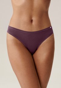 Fioletowy bikini z mikrofibry o gładkiej fakturze, niskim kroju i cienkim pasku, z małą metką logo z boku.