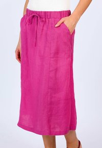 Long pink linen skirt with an elastic waist and drawstring, featuring side pockets and a relaxed fit. Smooth texture with slight sheen.
