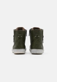 Grüne Lederstiefeletten mit Reißverschluss und gepolstertem Kragen. Weiße Gummisohlen mit strukturiertem Grip. Logodetail an der Ferse.