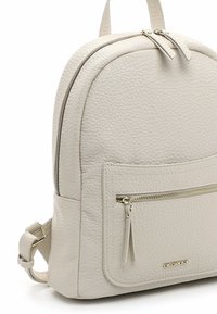Beige textured leather backpack with front zip pocket, double zipper closure, adjustable strap, and gold "EMILY & NOAH" logo plate.