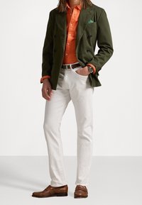 Olivgrön dubbelknäppt blazer, orange skjorta med knappar, vita byxor, bruna läderskor och en mönstrad näsduk.