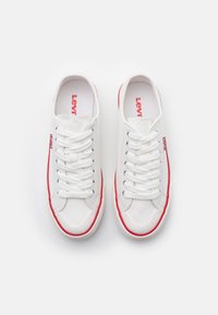 Sneakers bianchi in tela con dettagli rossi e suole in gomma. Presentano punta tonda, chiusura con lacci sul davanti e il marchio "Levi's" sui lati e sulla soletta.