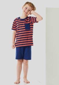 Striped t-shirt in orange and navy with a chest pocket, paired with navy shorts. Soft cotton material, short sleeves, and relaxed fit.