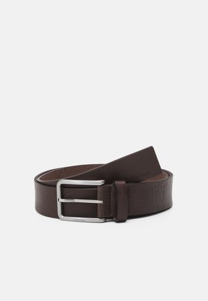 Cinto de pele castanha com uma textura suave, equipado com uma fivela de metal prateada e um detalhe de marca. O design é clássico e funcional.
