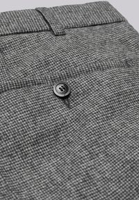 Grey houndstooth patterned fabric with a textured surface, featuring a black plastic button attached at the front.