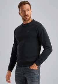 Donkerblauwe sweatshirt gemaakt van zachte stof met een ronde hals, raglanmouwen en een klein logo op de borst en mouw.
