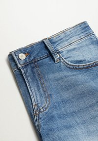 Vaqueros de mezclilla azul claro con costuras visibles, cierre de botón metálico y un ligero desgaste cerca de los bolsillos y la cintura.