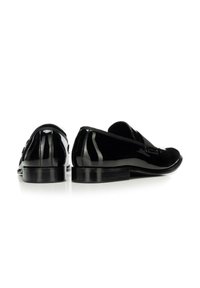 Schwarze Schuhe aus lackiertem Leder mit niedrigem Absatz, ausgestattet mit einer glatten Oberfläche und minimalistischem Design. Mit einem einfachen Riemen über dem Spann.