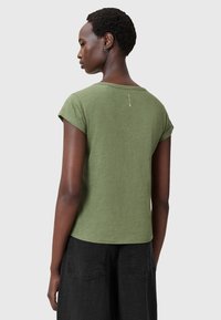 Olivengrøn kortærmet T-shirt med rund halsudskæring, en afslappet pasform og en diskret logo-detalje på ryggen. Tekstureret stof, casual stil.