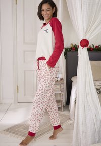 Rode en witte pyjama set met een top met een gebogen zoom, rode mouwen en een geborduurd ontwerp. De broek heeft een sneeuwvlokpatroon en rode boorden.