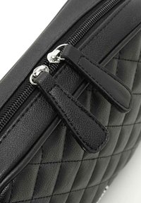 Borsa a busta nera trapuntata con esterno in pelle sintetica testurizzata, dotata di zip e tirazip in tonalità argento per un facile accesso.