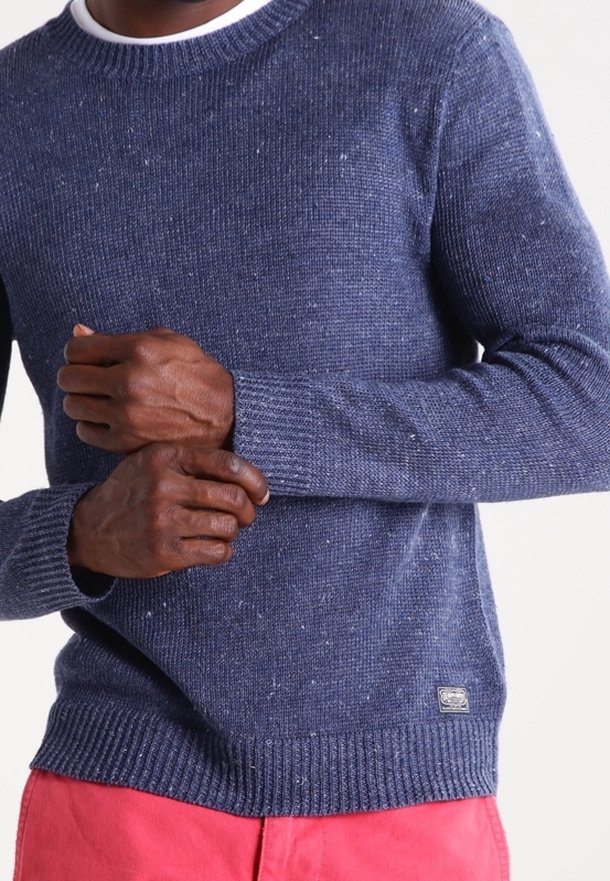 Pullover di colore navy lavorato a maglia con un motivo testurizzato, polsini e orlo a costine, dotato di un piccolo tag con logo sul lato inferiore. Realizzato in filato morbido.