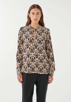 Zwarte blouse met lange mouwen en een geometrisch cirkelpatroon in crème en beige. Sleutelgatdetail bij de hals en licht gepofte mouwen.