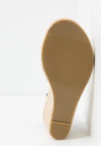 Semelle d'espadrille beige en caoutchouc texturé, avec une tige en jute tissée, un bout arrondi et un motif à rayures horizontales sur la base.