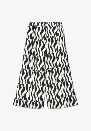 Pantaloni a gamba larga bianchi e neri con motivo a strisce ondulate disposte in stile scacchiera, distesi su uno sfondo bianco.