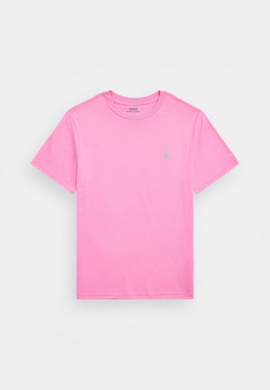 T-shirt rosa de algodão de manga curta com decote redondo, apresentando um pequeno logotipo verde no peito e uma textura suave e leve.