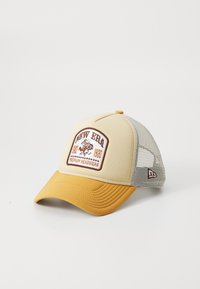 Gorra beige y mostaza con malla trasera, que presenta un parche de logotipo bordado en marrón y bordes de visera texturizados.