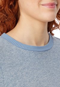 Suéter de algodón azul claro con un cuello acanalado. Presenta una tela suave y texturada con un patrón jaspeado y un corte holgado.