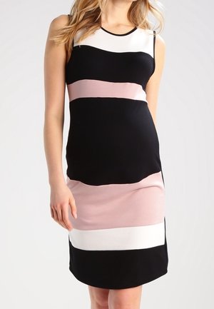 Woman wearing sleeveless knee-length dress with horizontal color blocks in white, black, and pale pink, standing with one arm relaxed.