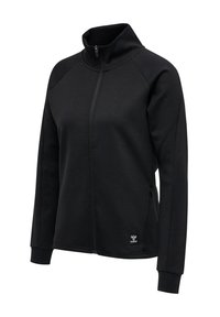 Veste noire avec fermeture éclair intégrale, col montant, manches longues, poches latérales et un petit écusson logo près de l'ourlet côté gauche.