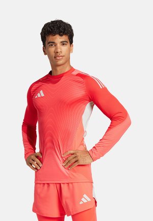 Langarm sporttop in felrood met een verlooppatroon, voorzien van witte accenten en logo. Gecombineerd met bijpassende shorts.