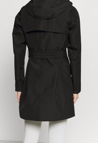 Cappotto impermeabile nero con cappuccio, vita con cintura e design a strati sul retro. Texture liscia e maniche lunghe. Stile minimalista.