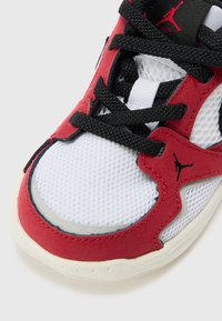 Sneaker con tomaia in suede rosso e rete, pannelli in tessuto bianco, lacci neri, suola cushioned e logo di marca nero sul lato.