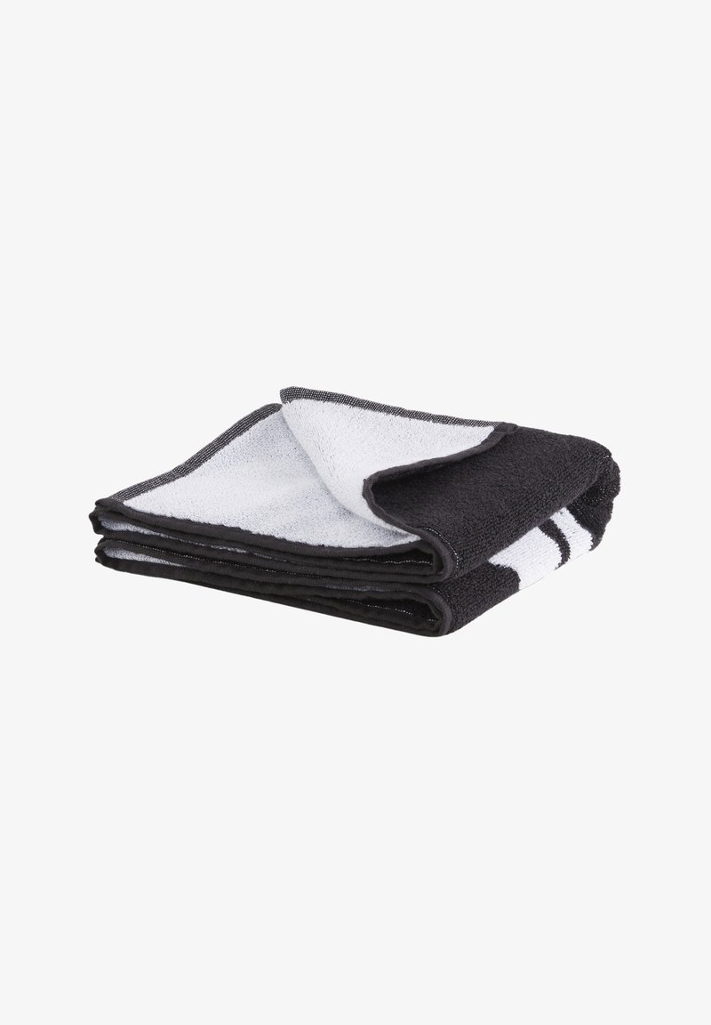 Toalla de rayas en blanco y negro doblada de forma ordenada, con una esquina volteada para mostrar ambos colores y la textura.