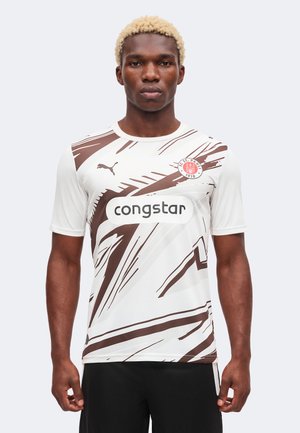 Mężczyzna w białej koszulce piłkarskiej z brązowymi abstrakcyjnymi pasami, herbem klubu St. Pauli, logo Puma i sponsorem Congstar.