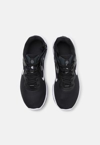 Scarpe da ginnastica nere con tomaia in rete, lacci e accenti bianchi. Presentano una suola ammortizzata e un colletto imbottito per il comfort.