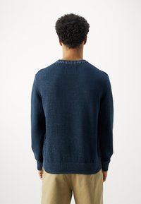 Marineblauer Strickpullover mit rundem Kragen, gerippten Bündchen und Saum. Strukturiertes Material mit dezenten schimmernden Details.