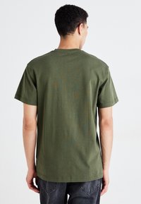 Olijfgroen katoenen T-shirt met een ronde hals en korte mouwen, met een gladde textuur en een relaxte pasvorm. Achteraanzicht zonder zichtbare logo's.
