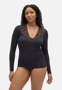 Camisa negra de manga larga con un diseño de escote en V de encaje negro transparente. Tejido suave con una forma ajustada, combinada con un pantalón a juego.