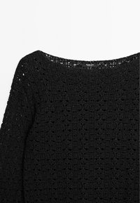 Schwarzer Strickpullover mit weitem Rundhalsausschnitt und langen Ärmeln, dessen Lochmuster seine Textur und sein Design betont.